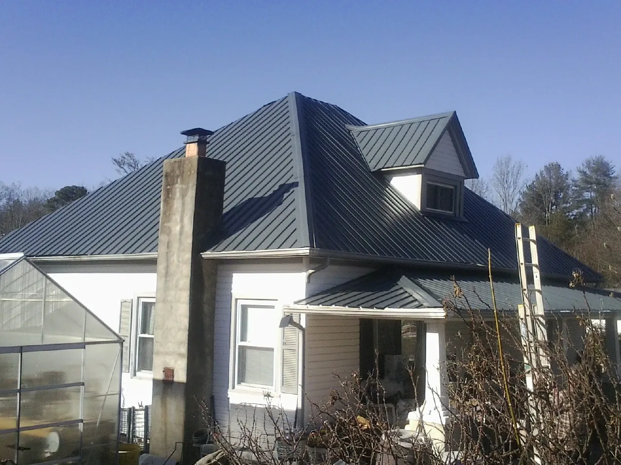 Dark blue standing seam metal roof on a white farmhouse with dormer — Slate & Tile Roof Repair by Roofing Brothers in Church Point