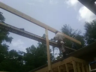 Carpenter setting a ridge beam over a new addition frame — Ice Dam Removal by Roofing Brothers in Church Point
