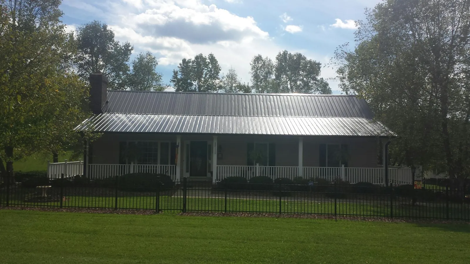 Gray metal roof on a brick ranch with a full width front porch — Gutter Guard Installation work by our crew in Church Point