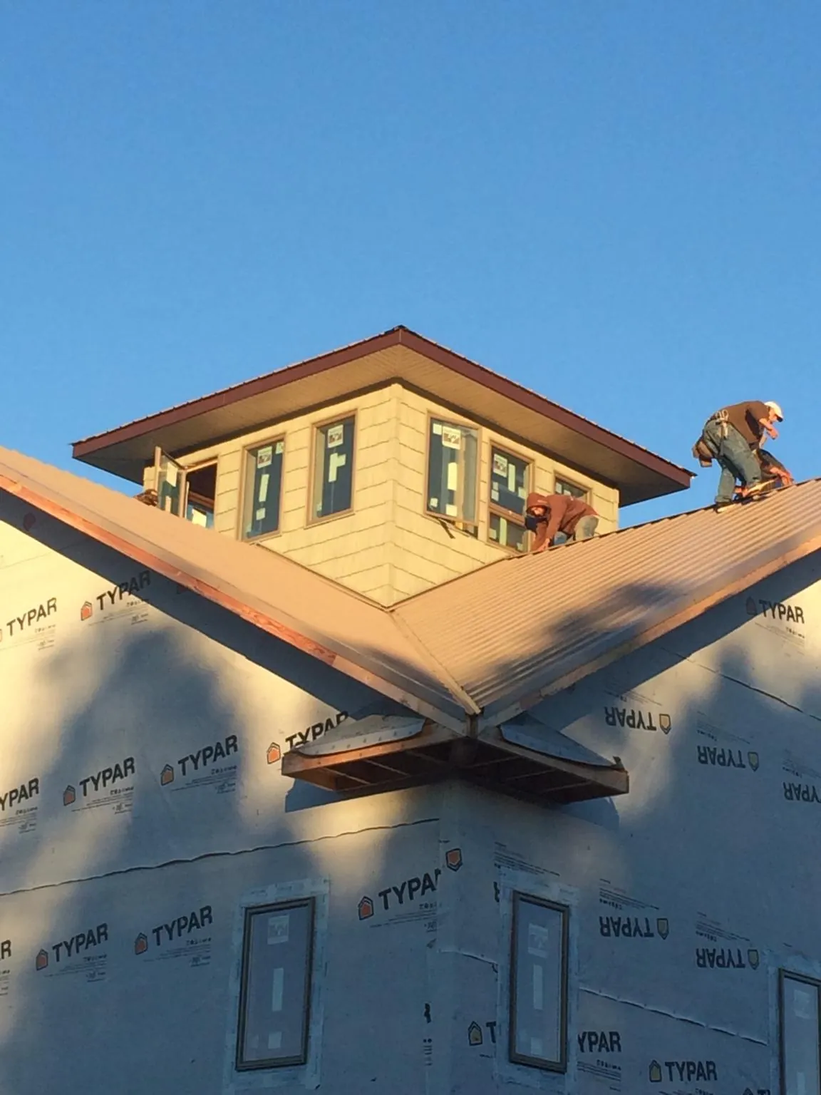 Roofers working around a rooftop cupola on a new metal roof at sunset — Roof Waterproofing in Church Point by Roofing Brothers
